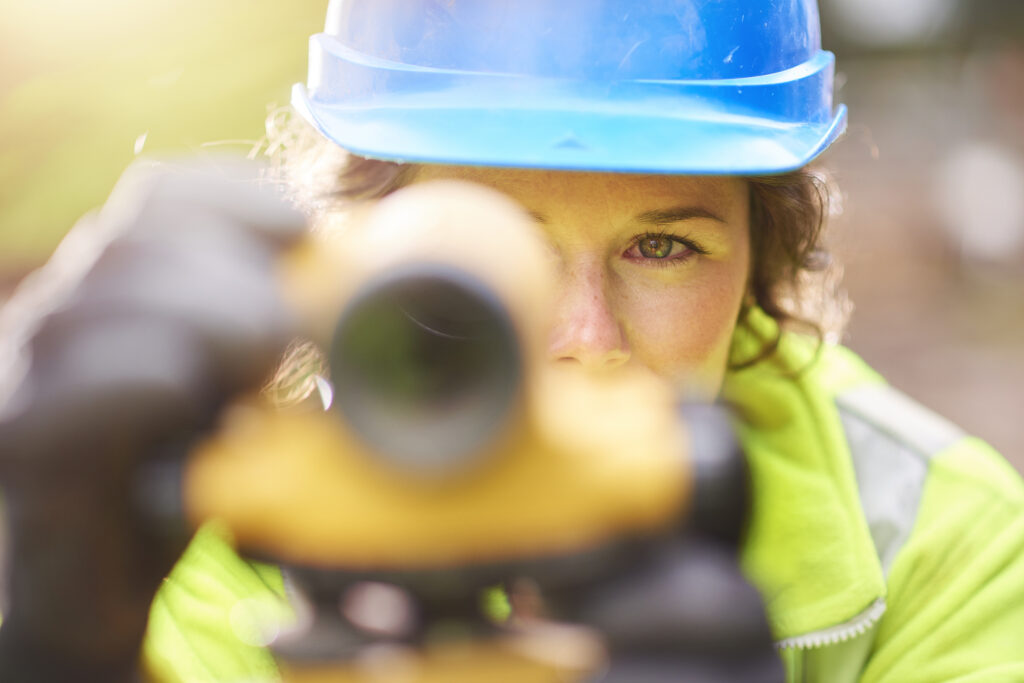 A female surveyor or engineer checking her levels on a building site